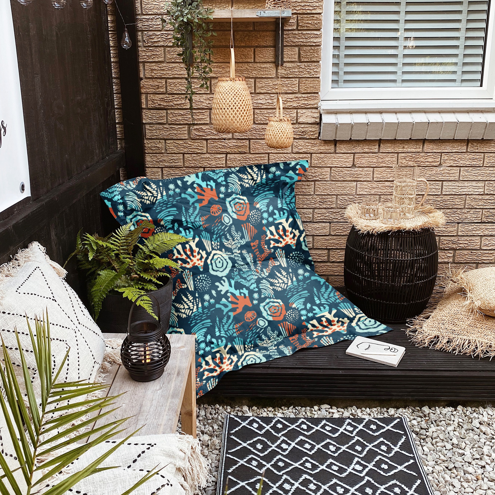 A photo of a patio with a bean bag chair and pillows on the ground.