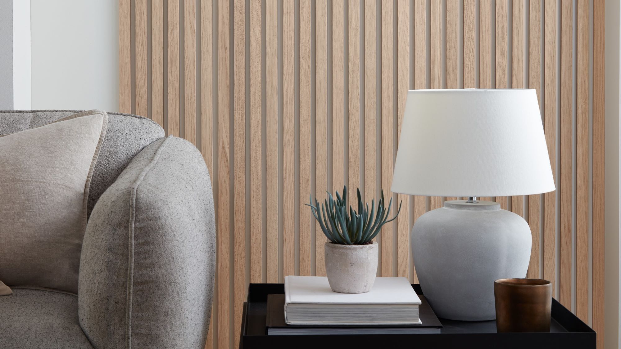 A wood panelled wall with a white lamp and a grey sofa